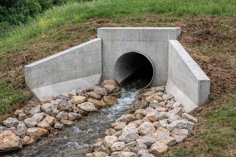 Concrete headwall and flared end section at stormwater drainage pipe outlet with riprap erosion protection